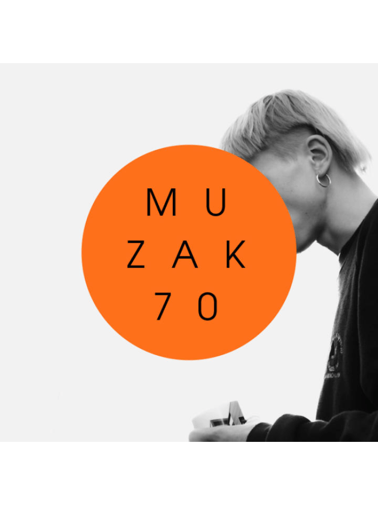 The image shows a person with light-colored hair looking down. A large orange circle with the text "MUZAK 70" is placed over their face. The image is in black and white, except for the orange circle. The person is holding something in their hands.