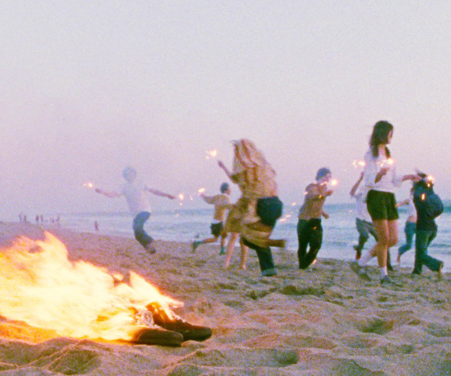 People ate dancing on the beach around a bonfire