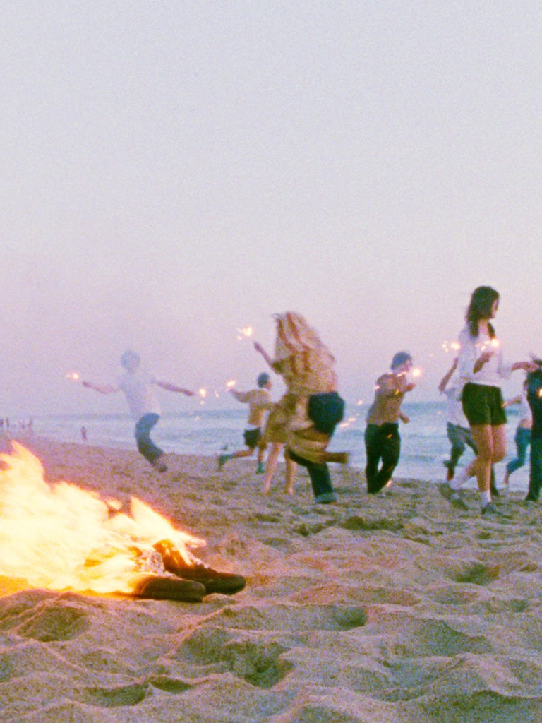 People ate dancing on the beach around a bonfire